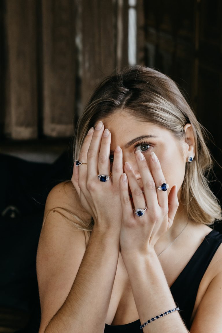 Lady covering face with hands wearing multiple engagement rings