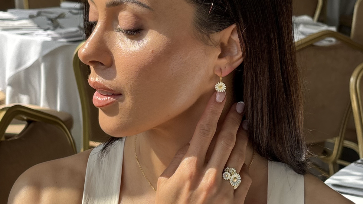 Woman sat by a window, sun shinning with multiple pieces of Georg Jensen dandelion jewellery