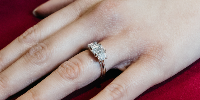 Person wearing an emerald cut diamond engagement ring