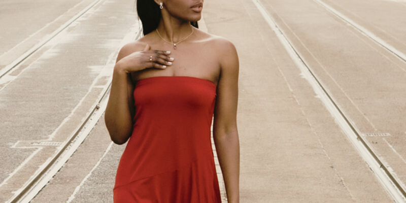 lady in red dress walking down centre of a road