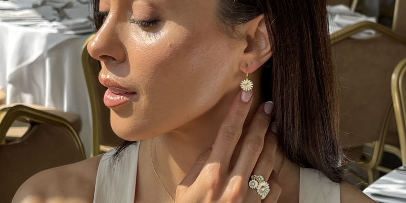Woman sat by a window, sun shinning with multiple pieces of Georg Jensen dandelion jewellery